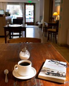 a cup of coffee and a book on a table at Casa Nanet Hotel in Mar del Plata