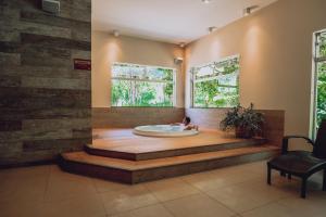 a person in a bath tub in a room with windows at Hotel Fazenda Salto Grande in Araraquara