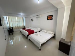a hotel room with two beds and a television at Hotel Luxor Pucallpa in Pucallpa
