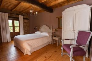 a bedroom with a white bed and a chair at Hotel Rural La Aceña in Quintanaluengos +9 photos