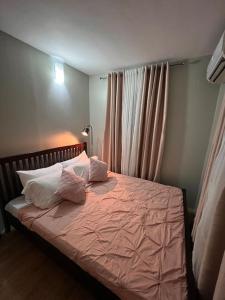 ein Schlafzimmer mit einem Bett mit rosa Laken und Kissen in der Unterkunft Casa Privado- 2 Bedroom House Near the Airport in Puerto Princesa