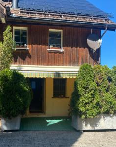 a wooden house with a porch and two bushes at Ferienwohnung in Stein AR in Stein