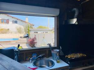 eine Küchentheke mit einem Waschbecken und einem Fenster in der Unterkunft Maison 160m2 Eysines in Eysines