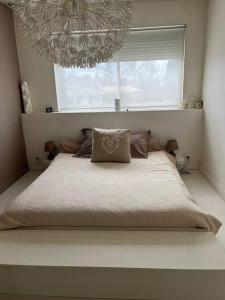ein Bett in einem Schlafzimmer mit einem Fenster und einem Kronleuchter in der Unterkunft Maison 160m2 Eysines in Eysines
