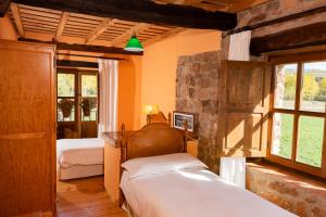 a bedroom with two beds and a stone wall at Hotel Rural La Aceña in Quintanaluengos