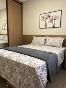 ein Schlafzimmer mit einem Bett mit einer grauen und weißen Bettdecke in der Unterkunft Flat Super Luxo - Rio Quente - Acesso Ao Rio in Rio Quente
