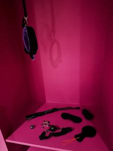 Habitación de color rosa con una pared de color rosa con teléfonos sobre una mesa en The Indulging Basement, en Barnsley