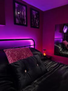 Dormitorio con cama con iluminación púrpura en The Indulging Basement, en Barnsley