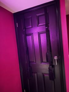 una puerta negra en una habitación rosa en The Indulging Basement, en Barnsley