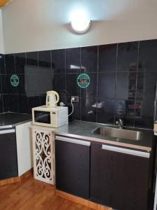 a kitchen with a microwave and a sink at Amplio departamento para 2 personas in Neuquén