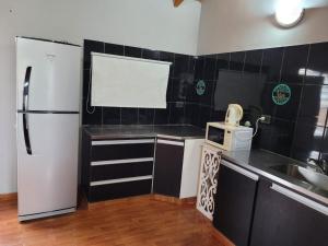 a small kitchen with a refrigerator and a sink at Amplio departamento para 2 personas in Neuquén