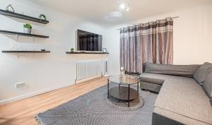 ein Wohnzimmer mit einer Couch und einem Glastisch in der Unterkunft Bright Cosy Cottage with Parking and Outdoor Patio in London