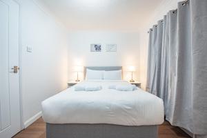 een slaapkamer met een groot wit bed met 2 kussens bij Bright Cosy Cottage with Parking and Outdoor Patio in Londen