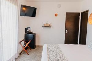 1 dormitorio con 1 cama y TV en la pared en HAU Holbox, Beach Front, en Isla Holbox