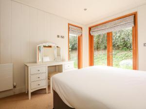 a white bedroom with a bed and a desk and a window at Harley's House in Oakham