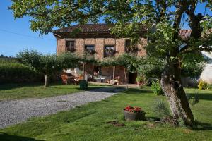 una gran casa de ladrillo con un árbol en el patio en Casa rural La Aceña en Quintanaluengos