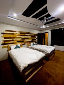 two twin beds in a room with a wooden wall at Lavender Cottage and Guest House in Skardu