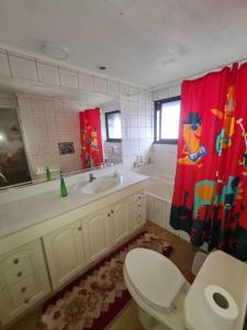 a bathroom with a toilet and a sink and a red shower curtain at Hospedaje Myrtha in Temuco