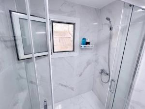 a white bathroom with a shower and a window at WSD Faliro New 1BD Apartment with Bal Near Alimos Marina in Athens