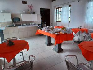 a kitchen with orange tables and chairs in a room at Torre do Sol in Praia do Frances