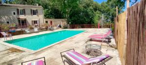 a swimming pool with chaise lounges next to a house at Le Mas du Coquelicot in Dions