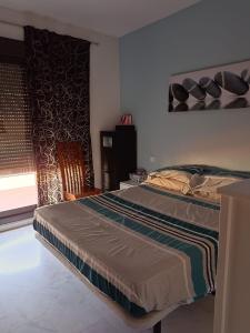 a bedroom with a bed and a chair and a window at Ático Mirabal in Mairena del Aljarafe