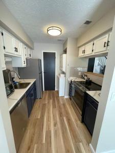 cocina con armarios blancos y suelo de madera en New Stylish Condo Monthly Rental, 