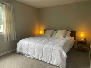 a bedroom with a large white bed with two lamps at New Stylish Condo Monthly Rental in Reminderville