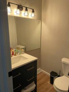 a bathroom with a sink and a toilet and a mirror at New Stylish Condo Monthly Rental in Reminderville