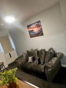a living room with a leather couch and a picture on the wall at Bradford Service accommodation in Bradford