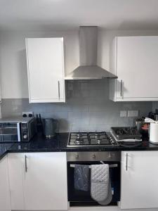a kitchen with white cabinets and a stove top oven at Perfect for family getaways in West Thurrock