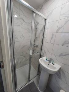 a white bathroom with a shower and a sink at Perfect for family getaways in West Thurrock