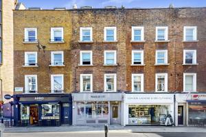 un gran edificio de ladrillo en una calle de la ciudad con tiendas en Park Lane Apartments Marylebone, en Londres