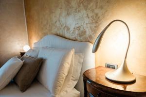 un letto bianco con cuscini e una lampada su un tavolo di Airport BEA Rooms ad Azzano San Paolo