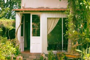 een klein huis met een witte deur in een tuin bij Vila Basi in Nguyệt Hạng