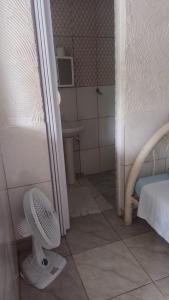 a bathroom with a fan in the corner of a room at Pousada Lambaris Pereque Guarujá in Guarujá