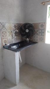 a room with a counter with a fan on the wall at Pousada Lambaris Pereque Guarujá in Guarujá