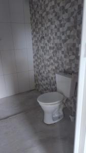 a bathroom with a white toilet in a room at Pousada Lambaris Pereque Guarujá in Guarujá