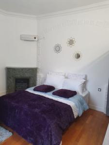 sypialnia z łóżkiem z fioletową pościelą i kominkiem w obiekcie Studio/Bourget/CDG/Villepinte w mieście Aulnay-sous-Bois
