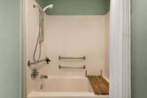 a bathroom with a bathtub with a wooden bench in it at MainStay Suites in Grand Rapids