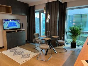 グディニャにあるModern Vero Apartments Yacht Parkのテーブルと椅子とテレビのあるリビングルーム