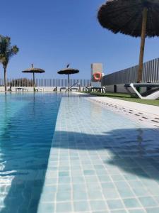 ein großer Pool mit Sonnenschirmen und Stühlen in der Unterkunft Turquesa Del Mar - Max Beach Golf - Ground Floor Apartment in Playa Flamenca