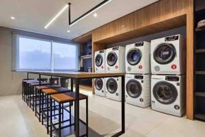 a laundry room with four washing machines and a table at Apto Supreme PUC in Porto Alegre
