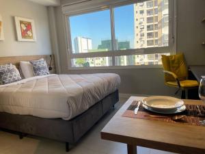 a bedroom with a bed and a table and a window at Apto Supreme PUC in Porto Alegre