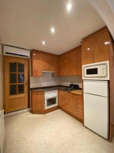 een keuken met houten kasten en een wit apparaat bij Amplio apartamento de obra nueva con A/C in Mataró
