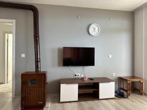 a living room with a tv and a table and a clock at Tirebolu Kaplan Apartman 