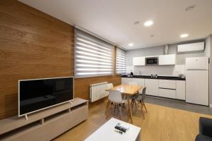 a living room with a large television and a kitchen at ALQUILAZ Apartamentos Turísticos in Zamora