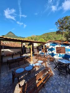 a patio with wooden tables and chairs and mountains at Ilha Grande Inn in Abraão