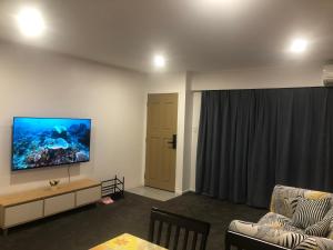 sala de estar con sofá y TV en la pared en Ali Motel en Auckland