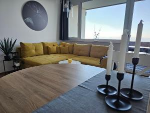 a living room with a table and a yellow couch at Gerlitzen-Apartments in Kanzelhöhe